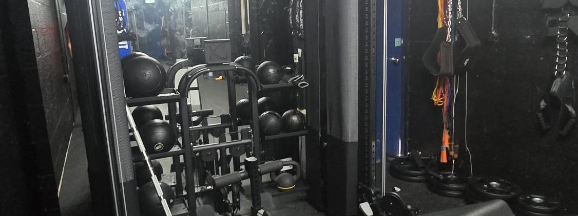 Black functional trainer cable machine with slam balls and a bench at MPL Box Fit