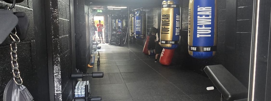 Row of TUF-WEAR punch bags down the MPL Box Fit training floor under hexagonal lighting