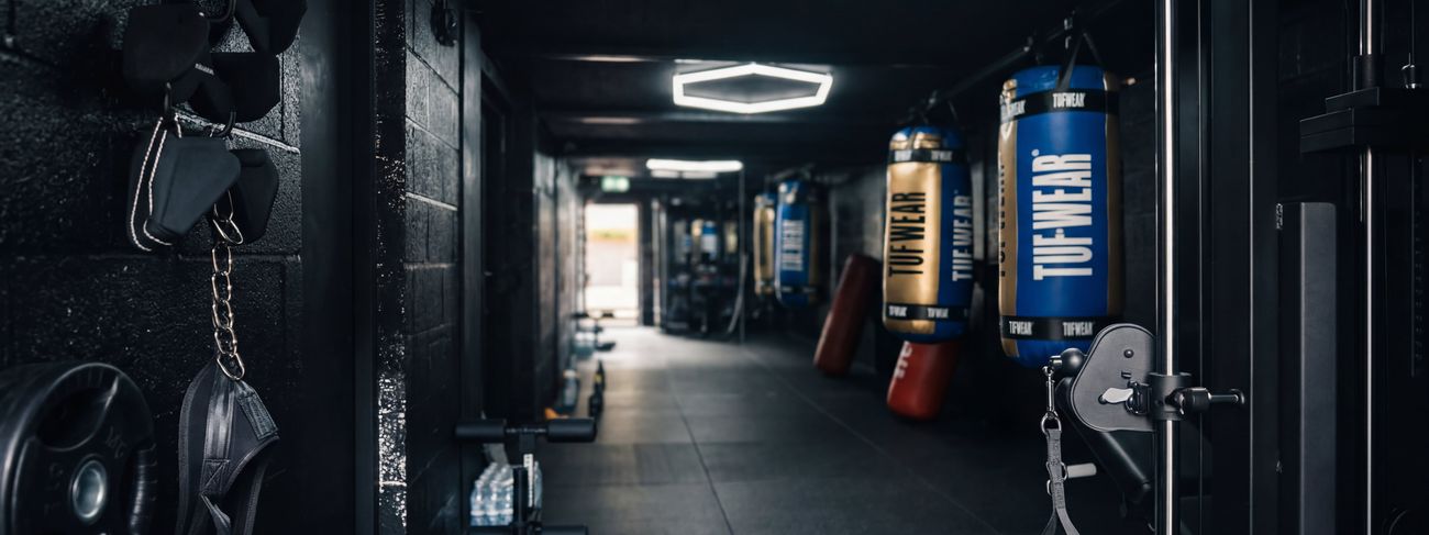 Row of TUF-WEAR punch bags down the MPL Box Fit training floor under hexagonal lighting